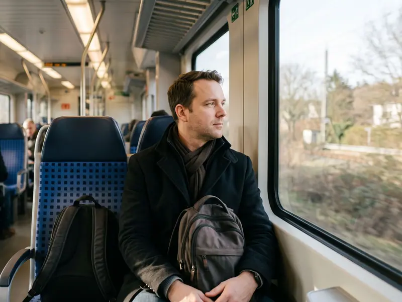 Pendler sitzt im Zug und blickt während der Fahrt aus dem Fenster